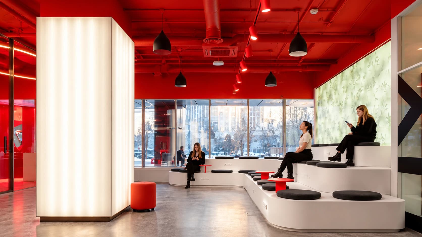 People seated in a lounge with a red ceiling and pendant lights
